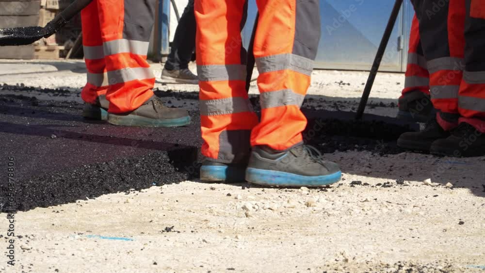 feet of unknown construction workers spread asphalt on the ground feet of unknown construction workers spread asphalt on the ground