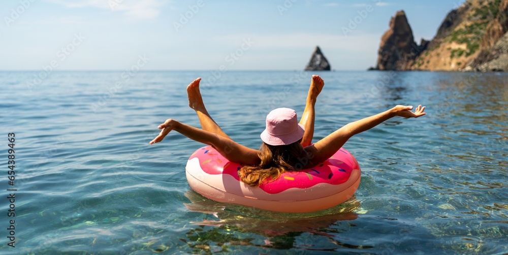 Summer vacation woman in hat floats on an inflatable donut mattress. Happy woman relaxing and enjoying family summer travel holidays travel on the sea. - obrazy, fototapety, plakaty 