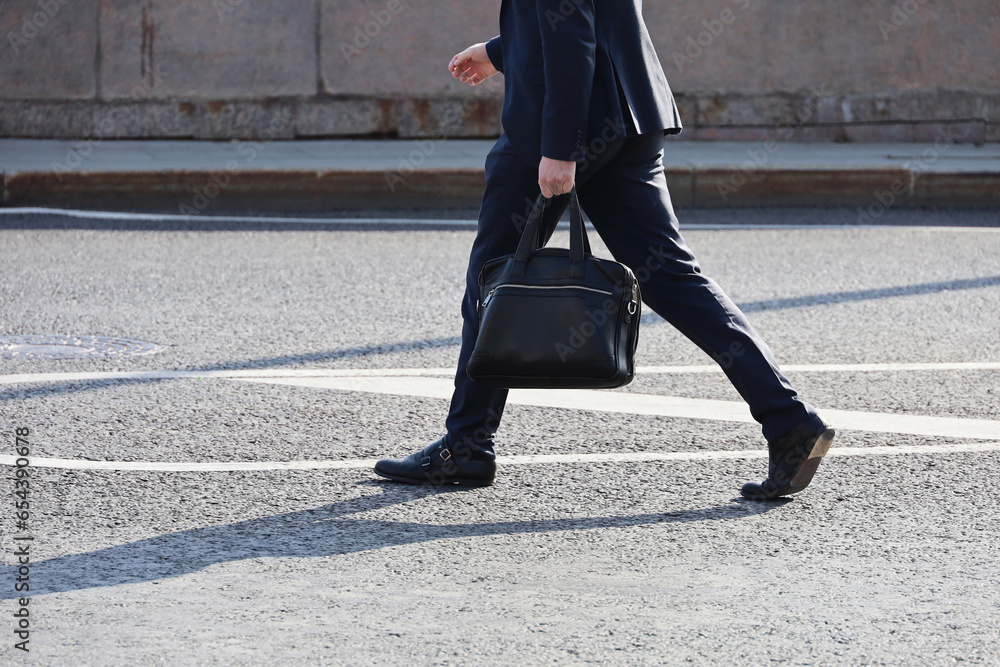 Man in a business suit walking down the street with briefcase in hand Man in a business suit walking down the street with briefcase in hand