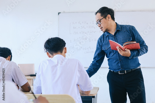 Fotografie Male high school Asian teacher teaching student in class at school