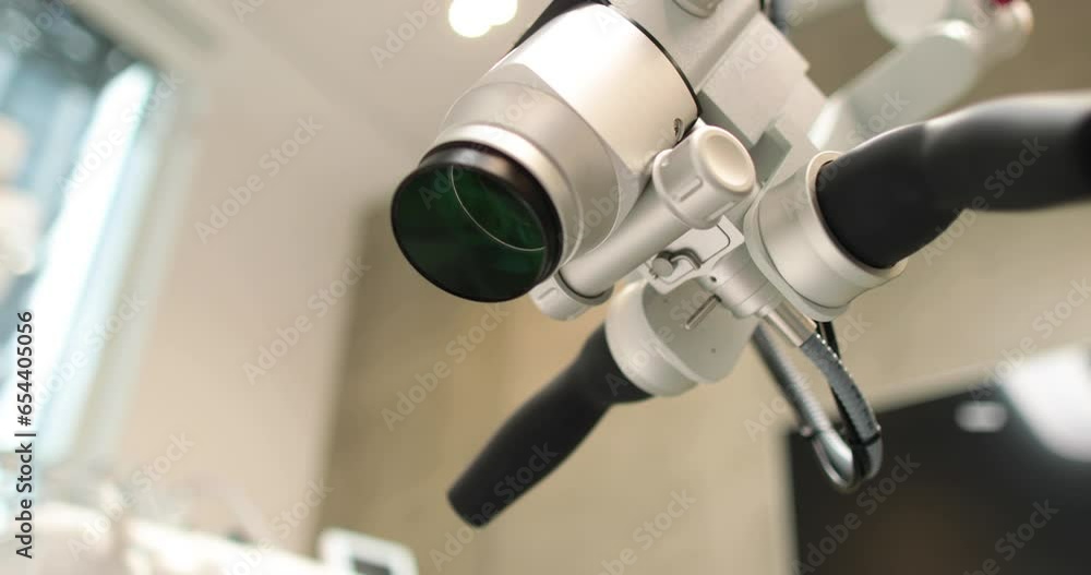 Close-up view of dental microscope indoors in medical clinic without people. Professional equipment with changing magnification and lens in a dental office in a hospital Close-up view of dental microscope indoors in medical clinic without people. Professional equipment with changing magnification and lens in a dental office in a hospital