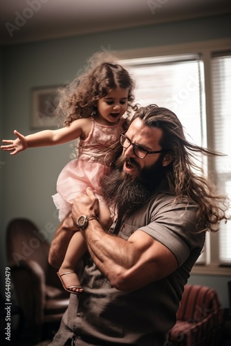 Father with long hair and beard twists and has with his daughter playing