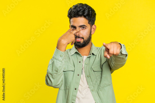 I am watching you. Confident attentive man pointing at her eyes and camera, show I am watching you gesture spying on someone. Handsome disappointed Indian guy isolated on yellow studio background