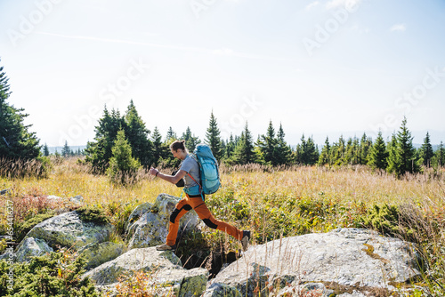 Guy tourist jumping on stones on a hike, overcoming a natural obstacle, mountain trekking, hiking. photo