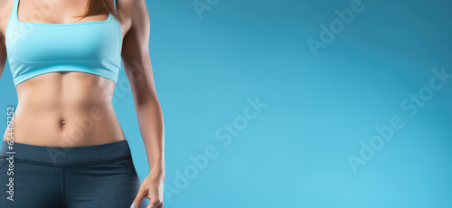 Cropped image of an athletic woman with beautiful flat belly isolated on pastel blue background with copy space. 