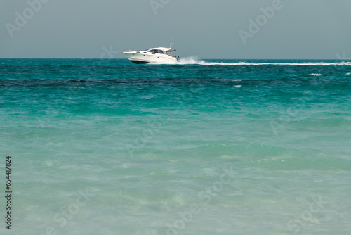 Blue clear sea, yacht, water, waves, clear sky. beach in Saadiyat island, United Arab Emirates. Beautiful seascape. © Alesia