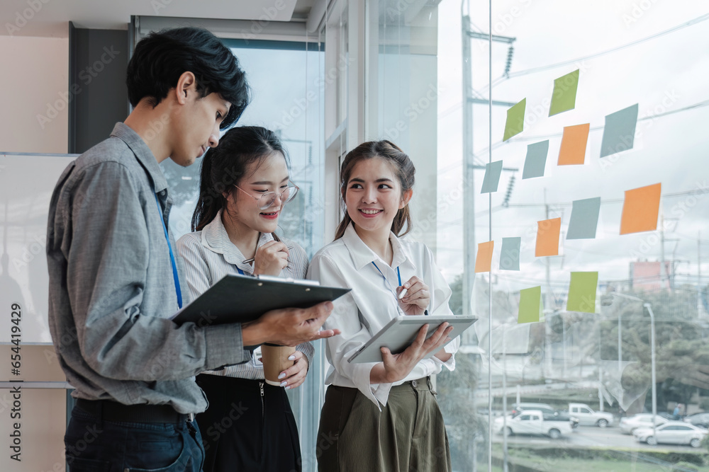 Fototapeta premium team employees busy brainstorming develop business ideas write on colorful sticky notes, concentrated colleagues share thoughts on pads on glass window