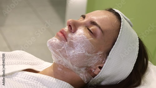 Cosmetologist applying cream with anesthesia on patient's face, portrait closeup view. Preparing skin for biorevitalization or thread lifting procedure. Woman in beauty clinic with doctor beautician.