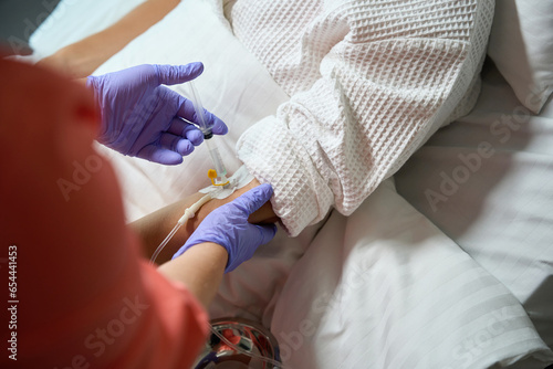 Nurse in protective gloves puts an IV on a patient