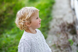 Surprised little girl in white sweater. Children's emotions. A child on the background of the grass in autumn