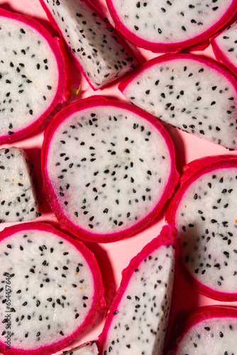 Slices of fresh white pitaya or dragon fruit on pink background, flat lay