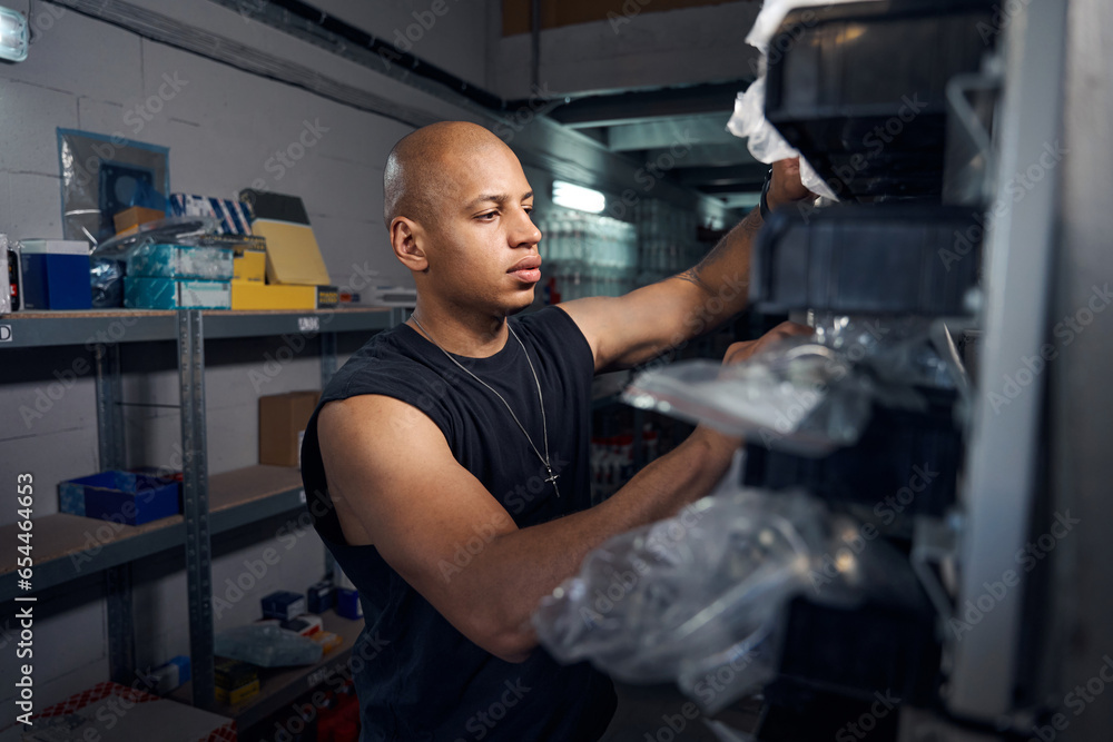 African American auto-mechanic looking for needed spare part in warehouse African American auto-mechanic looking for needed spare part in warehouse