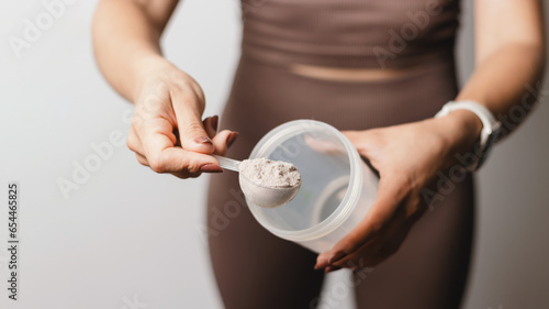 Canvas-taulu Athletic woman in sportswear with measuring spoon in her hand puts a portion of