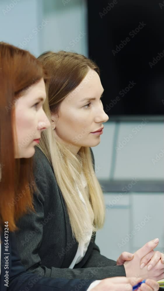 Vertical screen: Business women sitting together at table in office and nodding with agreement while listening to colleague behind camera. Business communication Vertical screen: Business women sitting together at table in office and nodding with agreement while listening to colleague behind camera. Business communication