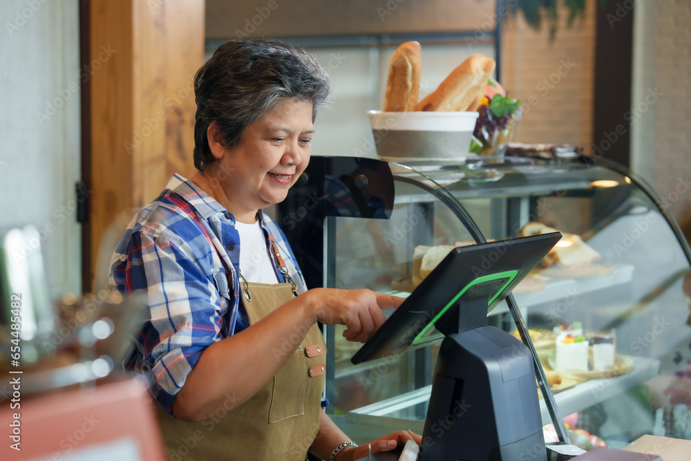 Φωτογραφία Gray-haired retired elderly business woman receives pension Standing in frontcash register counter, checking annual sales cafe's large volumes of coffee and bakery goods