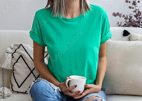 Women wearing blank heather green tshirt with copy space for your text or design with coffee cup. Christmas holiday tshirt mock up photo