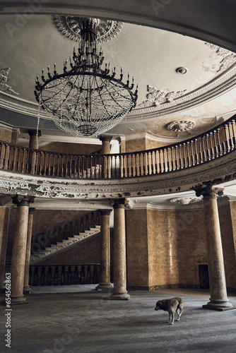 Abandoned soviet spa resort (sanatorium) Metallurg, in Tskaltubo, Georgia. Mezzanine floor, huge crystal luster in the centre. Columns on the background. Stray dog. Stalin empire style   photo