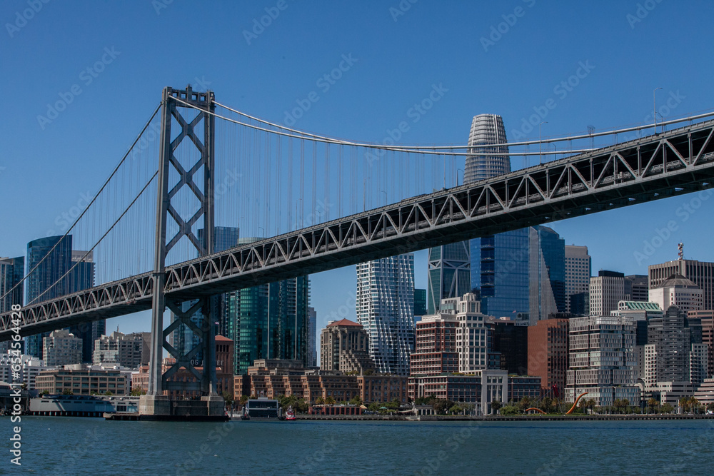 View from water of the San Francisco Bay Bridge in front of the Embarcadero and SF skyline on a clear day View from water of the San Francisco Bay Bridge in front of the Embarcadero and SF skyline on a clear day
