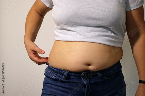 Close up of overweight young woman with fat belly after childbirth, pants doesn't fit