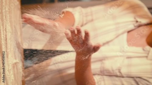 Vertical video. Girl Cook slams hands on flour in slow motion. A man makes dough. Baking dust and particles flying in the air. Concept of cooking and baking bread. High quality 4k footage