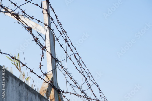 barbed wire on top of the wall fence. concept photo illustration of criminals escaping from prison