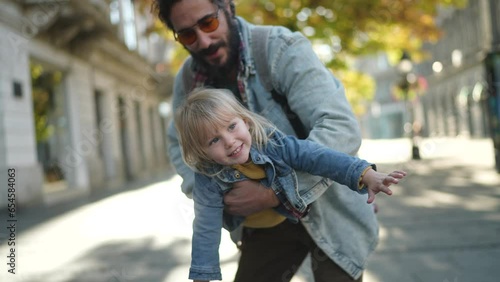 Young father playing airplane with his daughter while walking in the city
