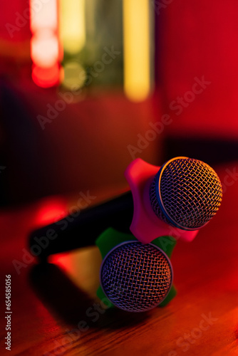 Two microphones with a pink and green attachment are lying on the table.  Karaoke, bar concept