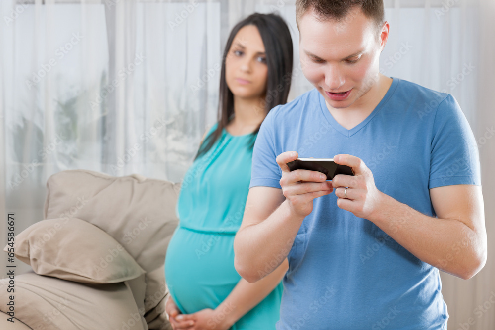 Expectant female concerned, partner immersed in gaming Expectant female concerned, partner immersed in gaming