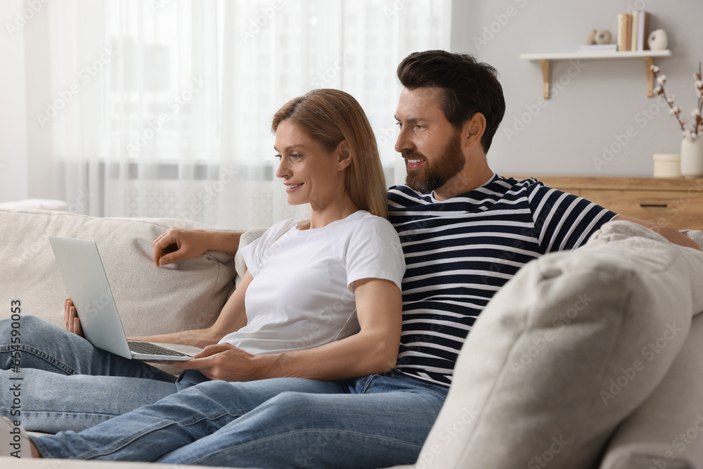 Happy couple with laptop on sofa at home Happy couple with laptop on sofa at home