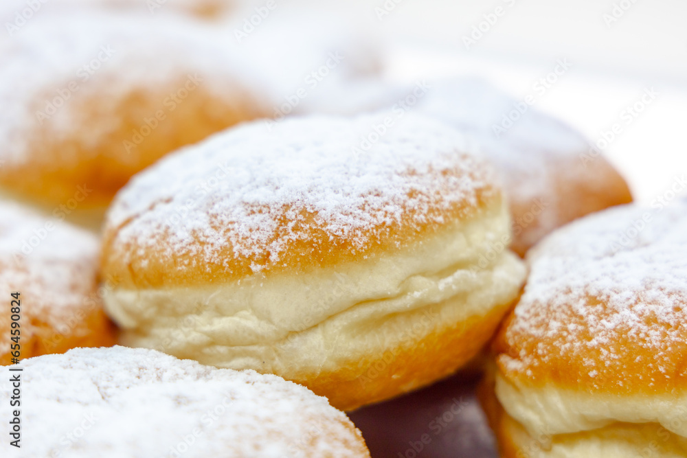 Fresh donuts covered in powdered sugar, close-up. Sweet pastries for breakfast
