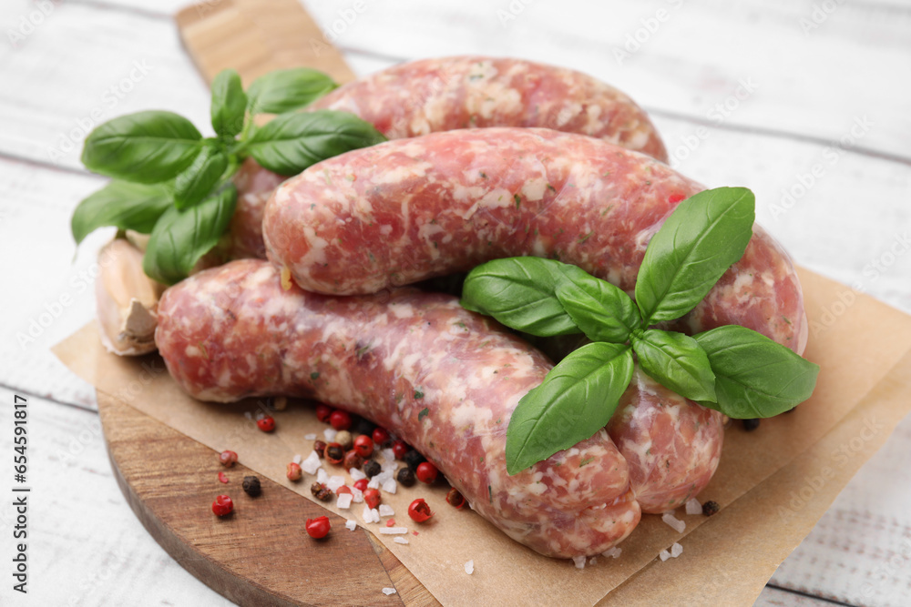 Raw homemade sausages and different spices on white wooden table, closeup