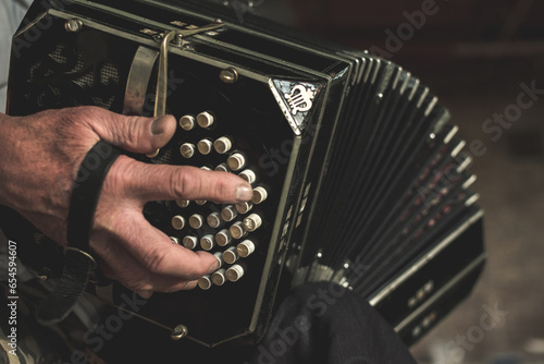 Aged male with white shirt and a wrinkled hand playing on bandoneon