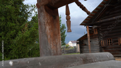 Wooden well and old houses. Media. Old wooden buildings in village. Rustic wooden buildings in Museum Reserve of History
