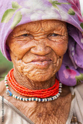 a bushmen San elderly woman from Central Kalahari, village New Xade in Botswana, in the yard of her home photo