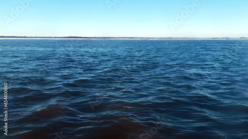 Fototapeta Naklejka Na Ścianę i Meble -  Beautiful view from moving boat on blue waves. Clip. Breathtaking view of blue sea waves on background of coast on horizon. Fast movement on blue waves