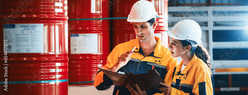 Photography Two factory workers or inventory inspector conduct professional inspection on hazardous chemical barrels in warehouse, chemistry storage workplace and industrial profession