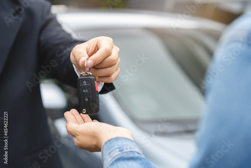 transportation rental automotive business concept. Close up hands of rental auto agent giving car remote key to client to travel sightseeing.