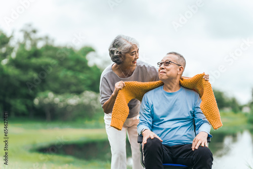 Love and support within an Asian family as they care for their elderly parents, symbolizing values of respect and devotion in aging together. Loving Care for Elderly Asian Couple in Wheelchair