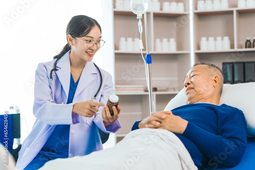 Caring female doctor provides attentive medical care to asian people elderly man lying in hospital bed  highlighting importance of expert healthcare and support during times of illness.