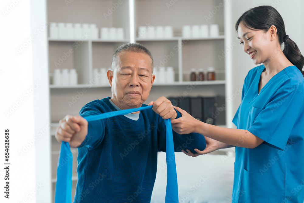 Obraz premium Asian people caregiver provides gentle support and encouragement to an elderly man during physical therapy session in a nursing care facility, promoting strength, mobility, and well-being.