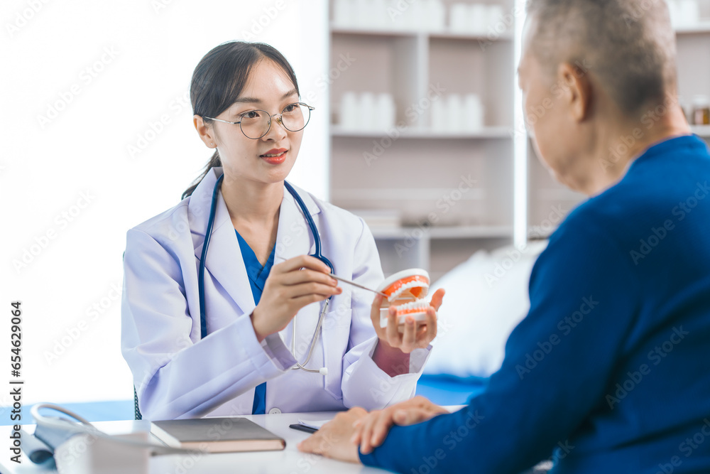 Fototapeta premium Asian people female dentist imparts valuable advice to elderly male patient, discussing root canal care, tooth extraction, tooth filling, emphasizing the importance of dental health and wellbeing.