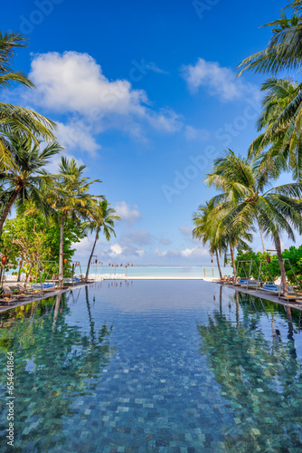 Panoramic wellbeing holiday landscape. Luxury beach resort hotel swimming pool leisure chairs beds under umbrellas  palm trees reflections blue sunny sky. Summer island seaside travel vacation scene