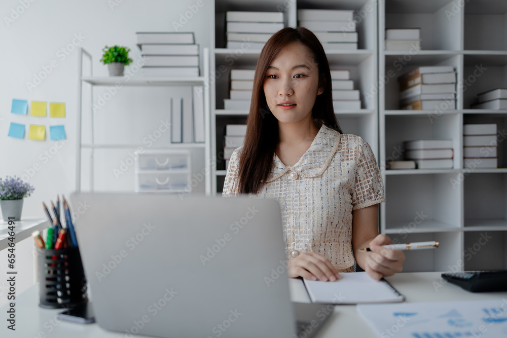 Young Asian woman, businesswoman in finance, businesswoman working in finance, planning finances for a startup company and reviewing financial statements. Financial management concepts. Young Asian woman, businesswoman in finance, businesswoman working in finance, planning finances for a startup company and reviewing financial statements. Financial management concepts.