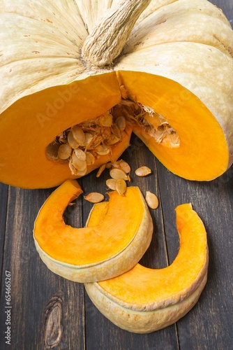Pumpkin slices with seeds on a wooden background. Selective focus.