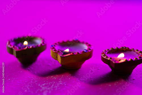 Close up of three diwali candles with copy space on purple background