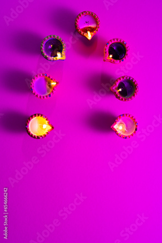 Close up of seven diwali candles with copy space on purple background