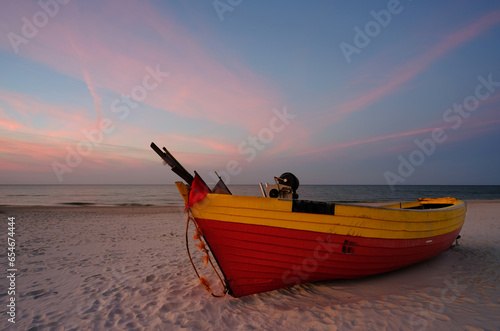 Łódz rybacka na bałtyckiej plaży , w pastelowych kolorach zachodzącego słońca