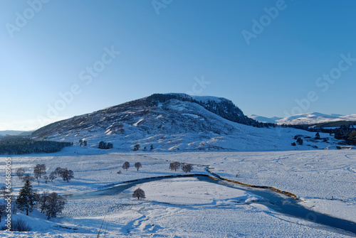 The River Dee flowing through the snow covered Valley above the Town of Braemar, with the crags of Creag Bhalg in the distance. © Julian