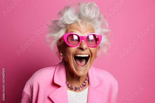 cheerful and funny happy old woman in vivid shine pink background © wai