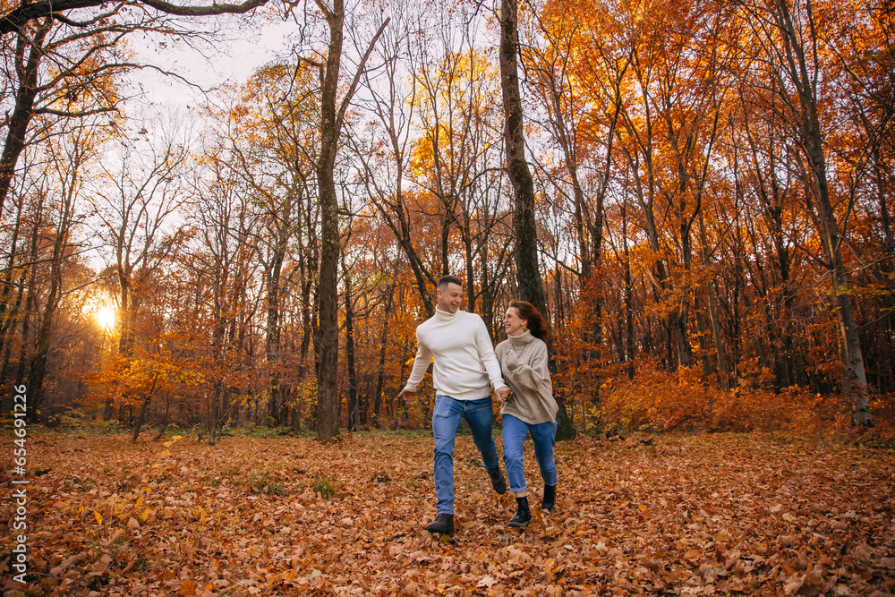 cheerful couple runs in the autumn park. covered with yellow foliage. Autumn walk in the fresh air. Two lovers in an autumn park. Romantic dates cheerful couple runs in the autumn park. covered with yellow foliage. Autumn walk in the fresh air. Two lovers in an autumn park. Romantic dates